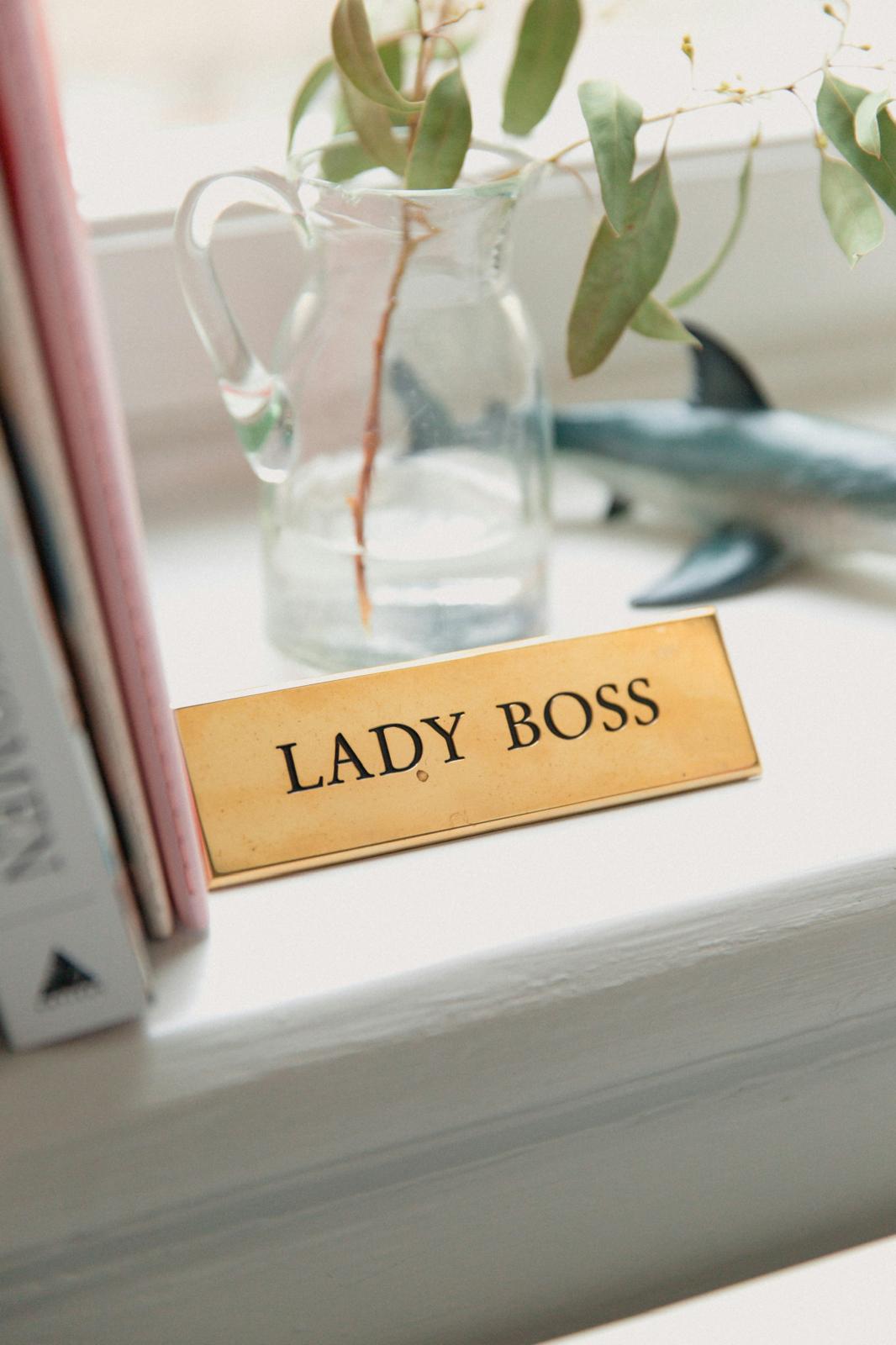 A “Lady Boss” nameplate on a desk beside a plant