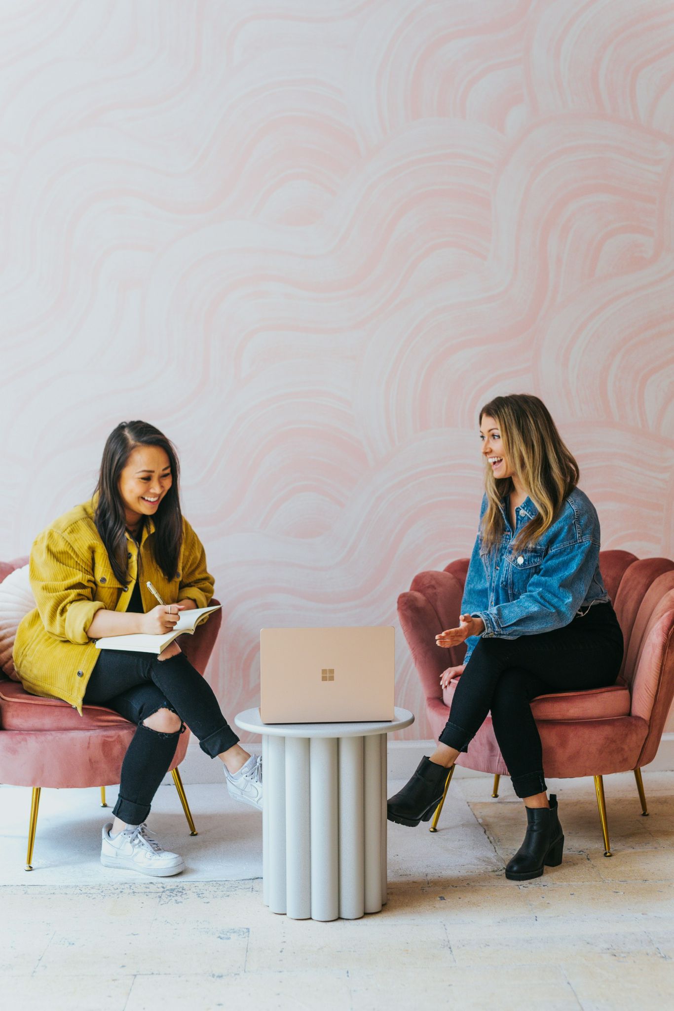 Two women in conversation on pink armchairs