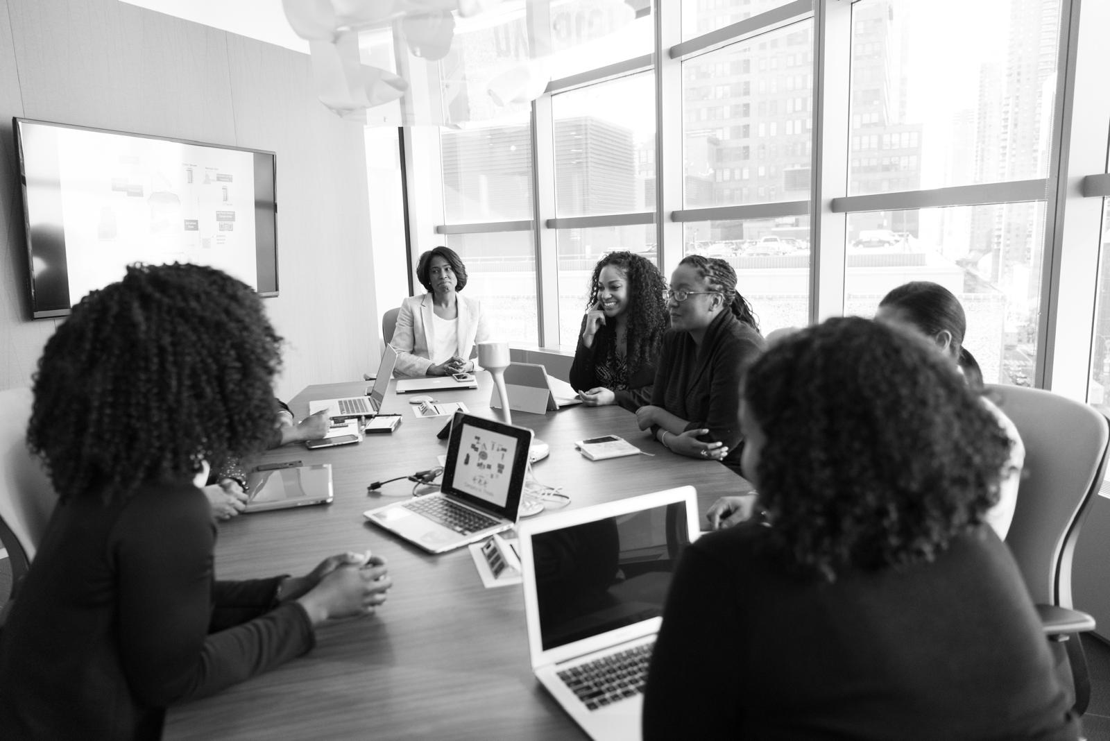 Black-and-white photo of women meeting around a table with laptops